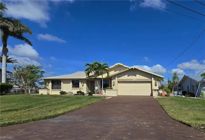 Ranch-style home featuring a garage and a front lawn