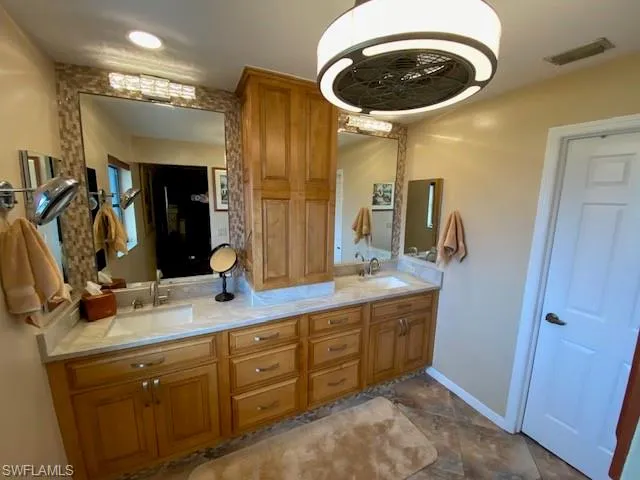 Full bath featuring visible vents, a sink, baseboards, and double vanity