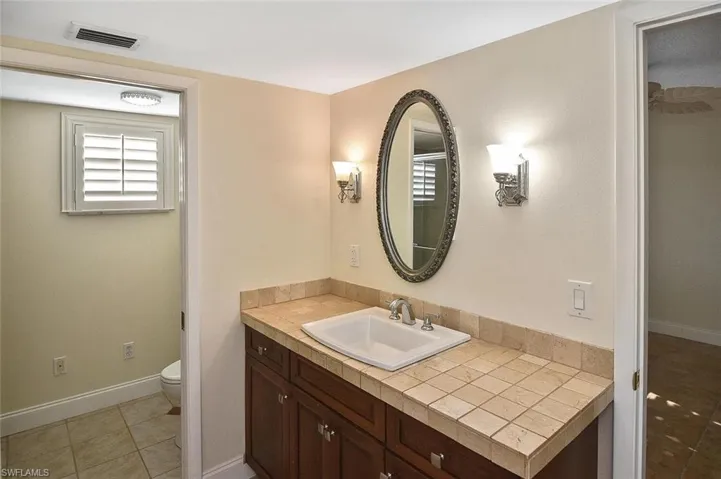 Full bathroom with vanity, healthy amount of natural light, and light tile patterned floors