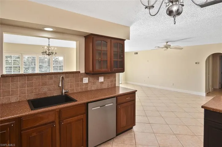 Kitchen with a chandelier, dishwasher, tasteful backsplash, light tile patterned flooring, and arched walkways