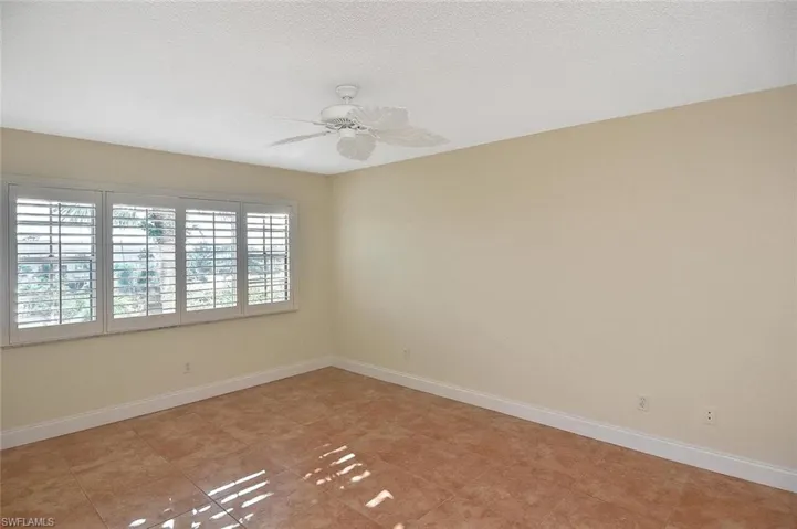 Empty room featuring ceiling fan, a textured ceiling, and light tile patterned floors