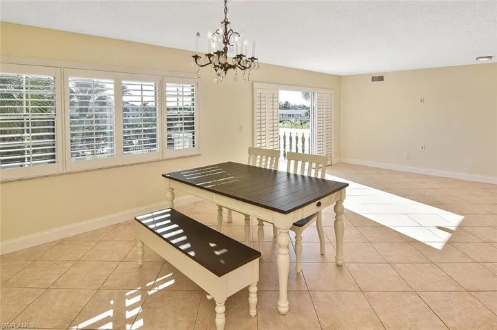 Dining area featuring light tile patterned floors, a chandelier, and a textured ceiling