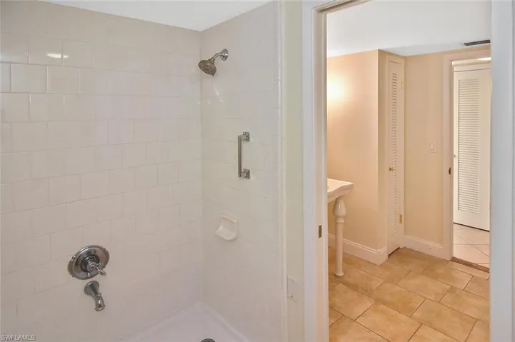 Bathroom featuring a tile shower, a closet, and light tile patterned floors