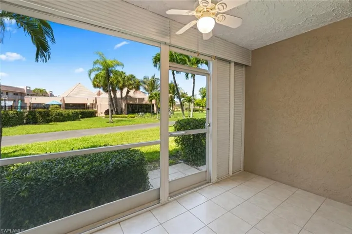 Screened patio featuring tile flooring, textured walls, and a ceiling fan with light fixture