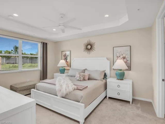 Carpeted bedroom with ceiling fan and a tray ceiling