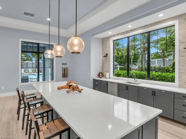 Kitchen featuring a kitchen island, a tray ceiling, a breakfast bar, hanging light fixtures, and sink