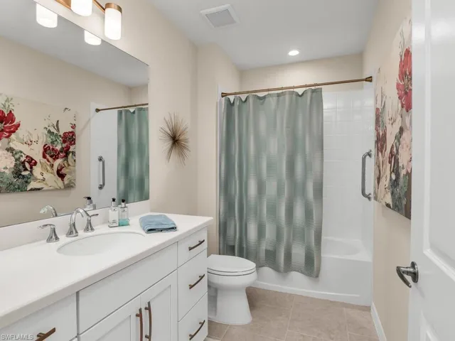 Full bathroom with tile patterned floors, toilet, shower / tub combo with curtain, and vanity