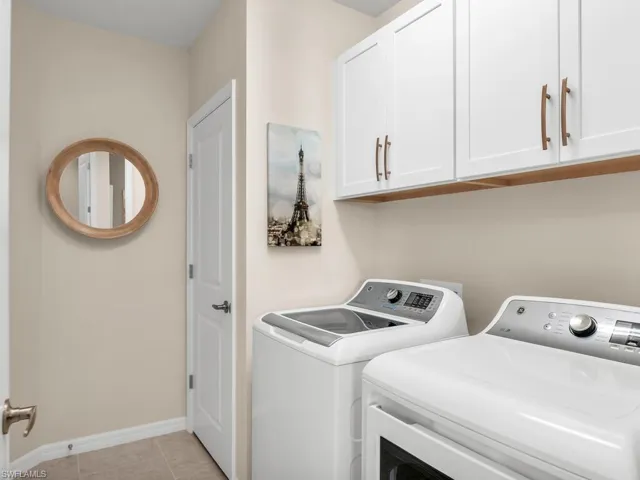 Washroom featuring washing machine and clothes dryer, cabinets, and light tile patterned floors