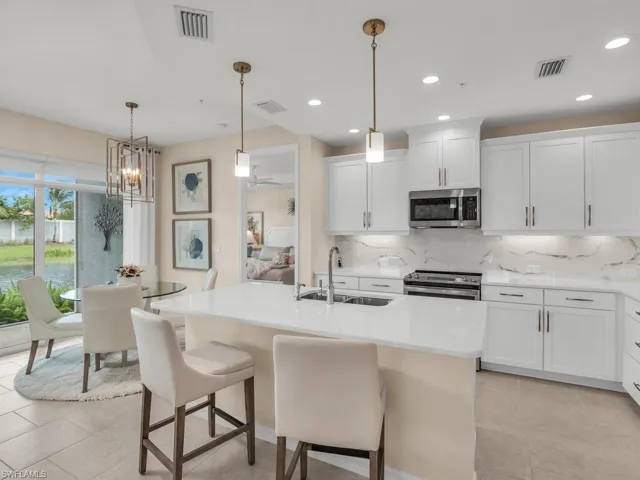 Kitchen featuring white cabinets, appliances with stainless steel finishes, sink, light tile patterned flooring, and tasteful backsplash