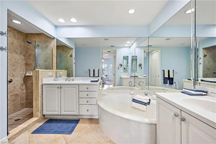 Full bathroom with a stall shower, light tile patterned floors, two vanities, a bath, and recessed lighting