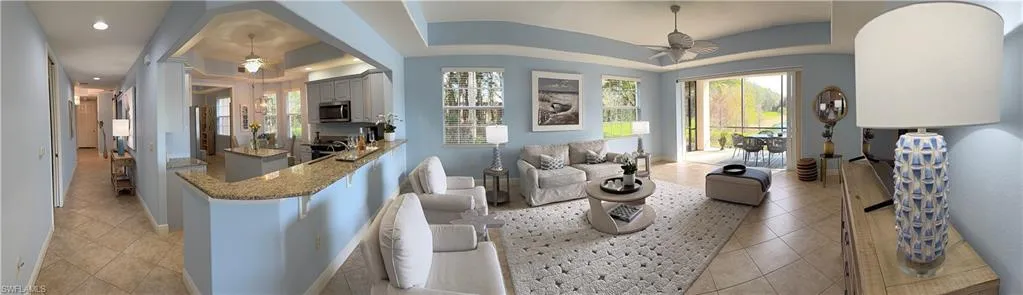 Living room featuring a ceiling fan, light tile patterned floors, and a tray ceiling