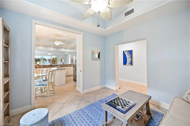 Living room with ceiling fan, a raised ceiling, and light tile patterned flooring
