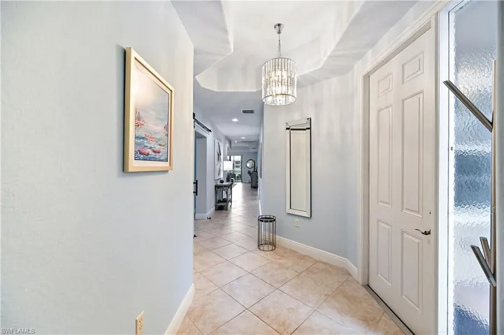 Corridor featuring a chandelier and light tile patterned floors