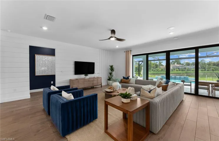 Living area with light wood finished floors, ceiling fan, wood walls, and recessed lighting