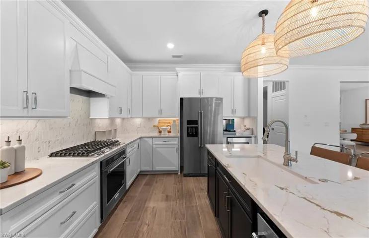 Two tone kitchen with light stone counters, two tone color scheme, stainless steel appliances, dark wood finished floors, and tasteful backsplash