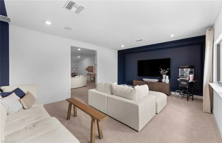 Carpeted living area with recessed lighting and baseboards
