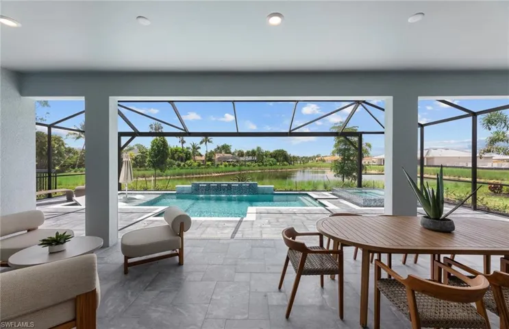 Integrated pool / hot tub featuring a sunroom, a patio, glass enclosure, and a water view