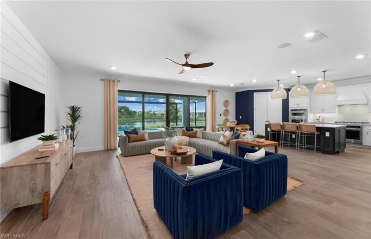 Living room with light wood finished floors, ceiling fan, recessed lighting, a water view
