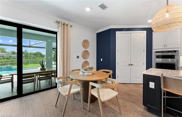 Dining room with crown molding, wood tiled floors, recessed lighting, and a water view