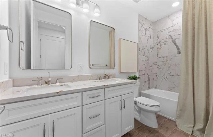Bathroom featuring double vanity, shower / tub combo, wood tiled floors, and recessed lighting