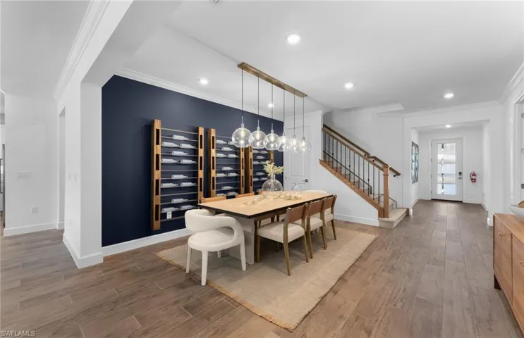 Dining room with ornamental molding, light wood-style flooring, beverage cooler, and recessed lighting