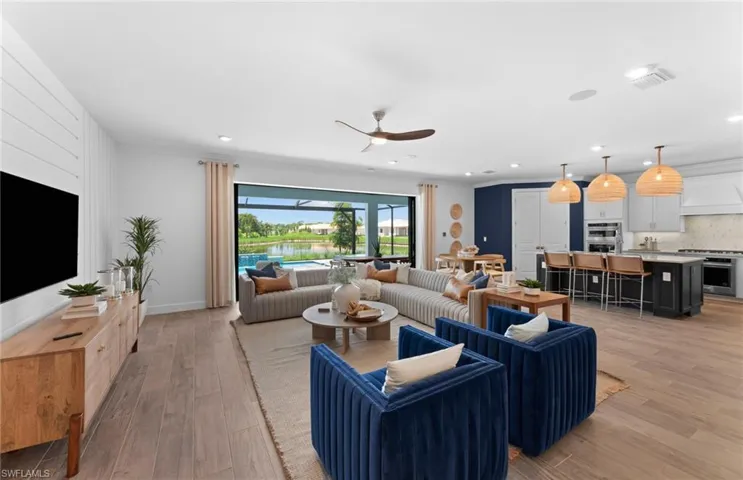 Living area with ceiling fan, light wood finished floors, recessed lighting, and a water view