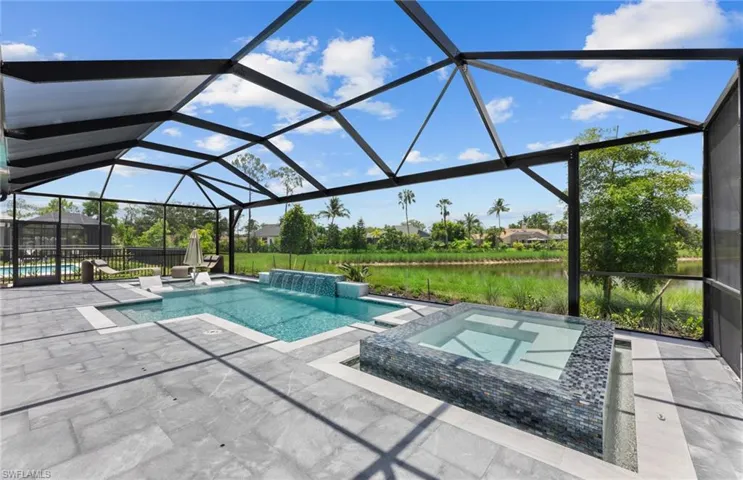 Relaxing pool / spa with a sunroom, glass enclosure, a patio area, and a water view