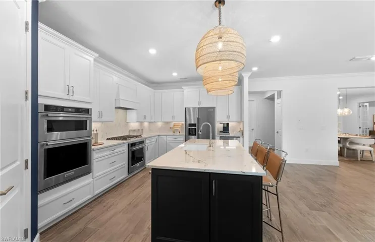Kitchen featuring tasteful backsplash, a breakfast bar area, stainless steel appliances, ornamental molding, and a center island with sink