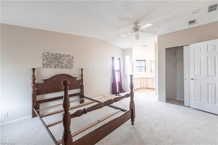 Bedroom with light carpet, a textured ceiling, vaulted ceiling, and visible vents