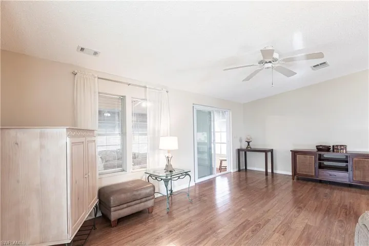 Sitting room with visible vents, wood finished floors, ceiling fan, and a textured ceiling