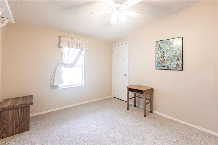 Carpeted bedroom featuring baseboards, a textured ceiling, vaulted ceiling, and a ceiling fan