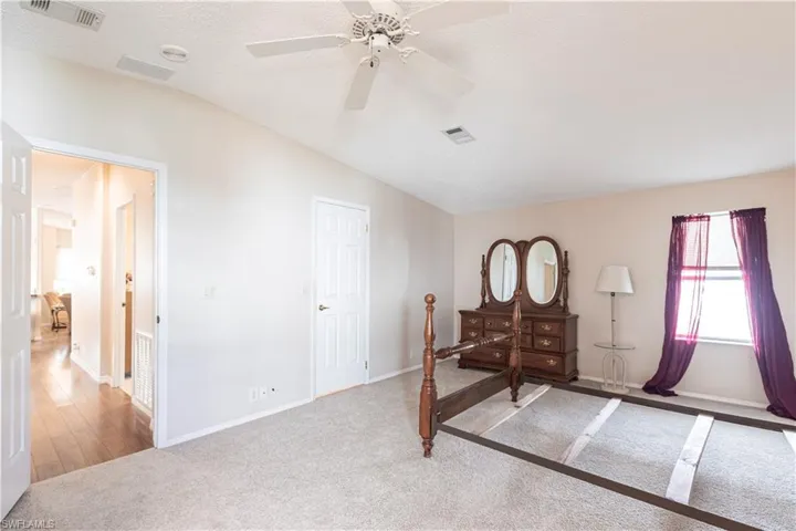 Carpeted bedroom featuring a textured ceiling, visible vents, vaulted ceiling, and a ceiling fan
