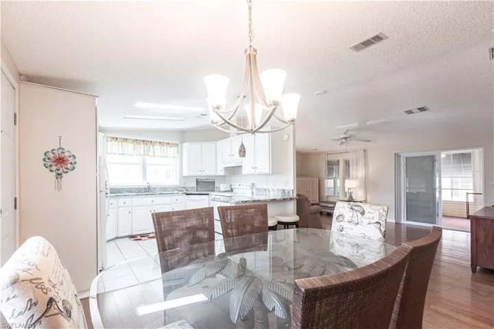 Dining area with light wood-type flooring, ceiling fan with notable chandelier, a textured ceiling, and visible vents