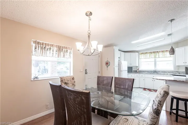 Dining area with baseboards, a textured ceiling, light wood-style flooring, and a chandelier