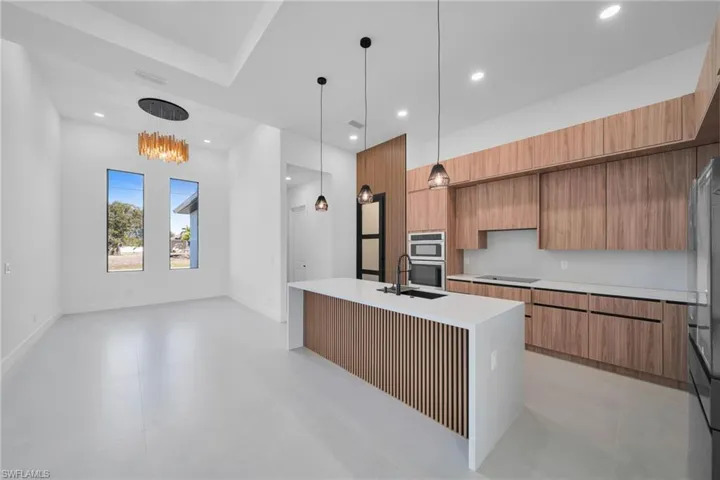 Kitchen with a center island with sink, modern cabinets, wood finish cabinets, and light stone countertops