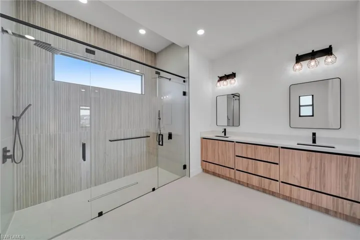 Bathroom featuring double vanity, a stall shower, and recessed lighting