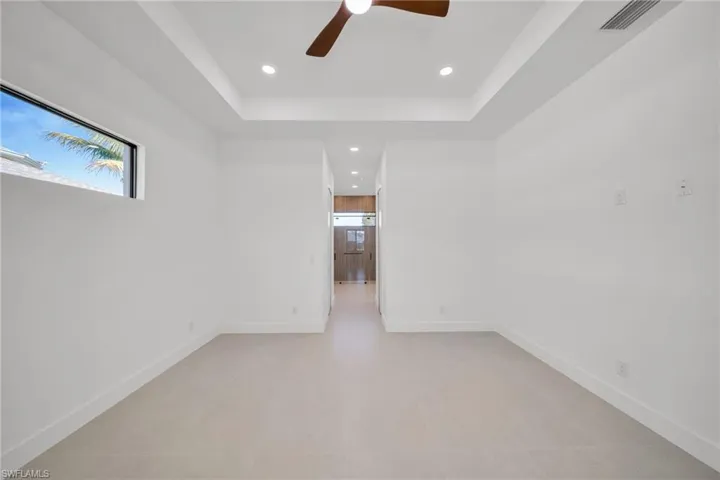 Empty room featuring recessed lighting, ceiling fan, and a tray ceiling