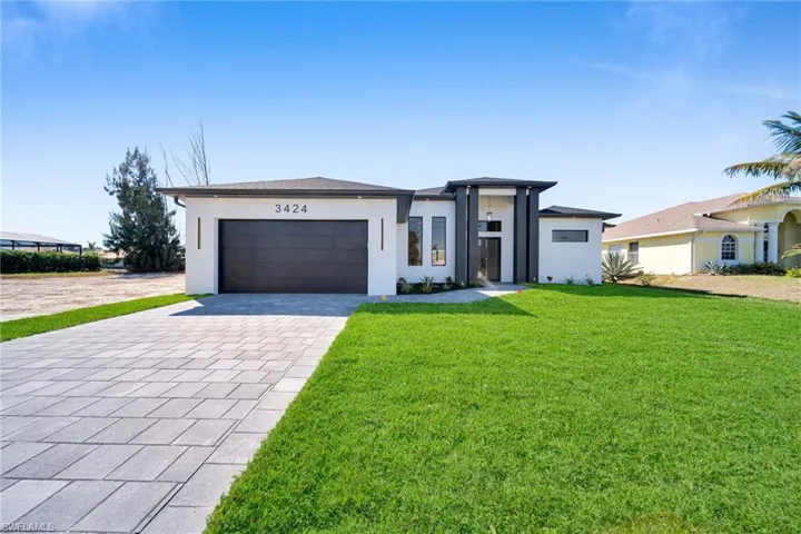 Prairie-style home featuring decorative driveway, a garage, stucco siding, and a front lawn
