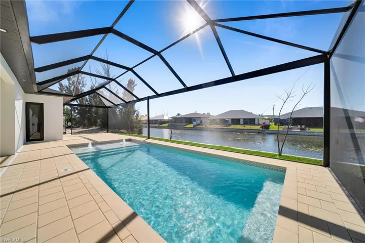 Swimming pool with a sunroom, glass enclosure, a water view, a residential view, and a patio area