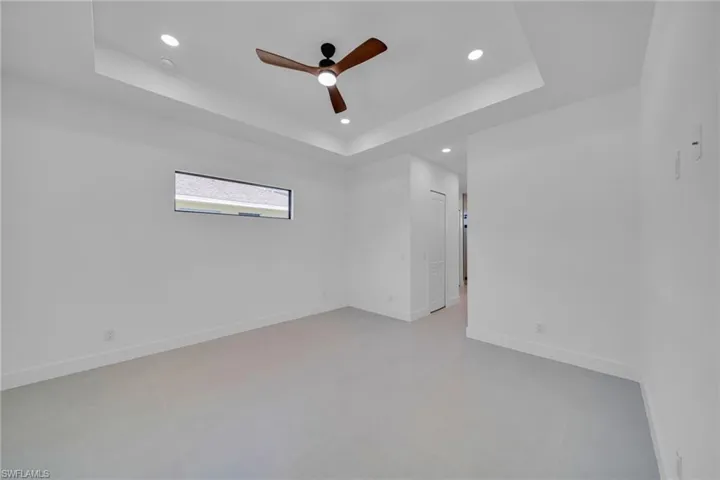 Empty room with ceiling fan, recessed lighting, and a raised ceiling