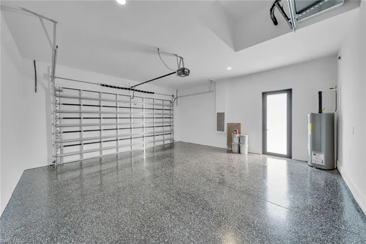 Garage featuring recessed lighting, electric panel, and electric water heater