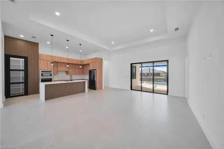 Kitchen featuring open floor plan, modern cabinets, a center island with sink, a high ceiling, and freestanding refrigerator