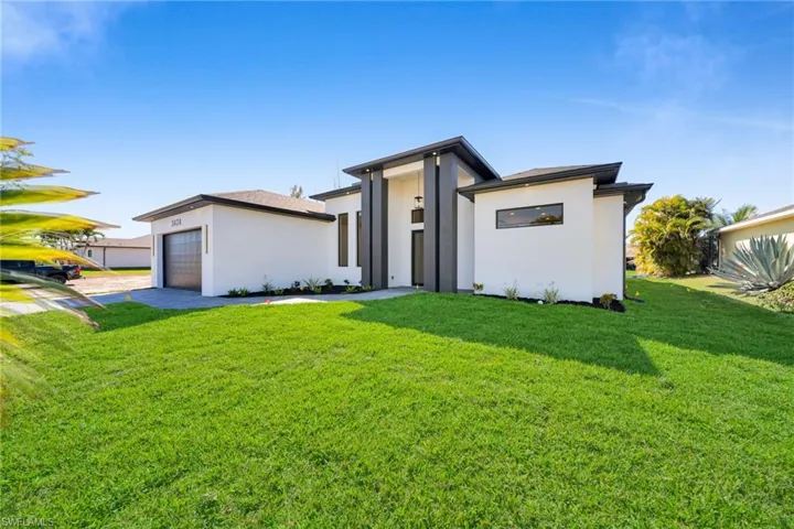 View of front facade with a front lawn, a garage, stucco siding, and concrete driveway