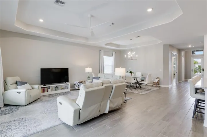 Living room with a tray ceiling, light hardwood / wood-style flooring, and a wealth of natural light