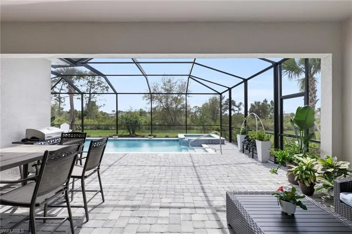 View of swimming pool featuring a lanai, an in ground hot tub, and a patio area