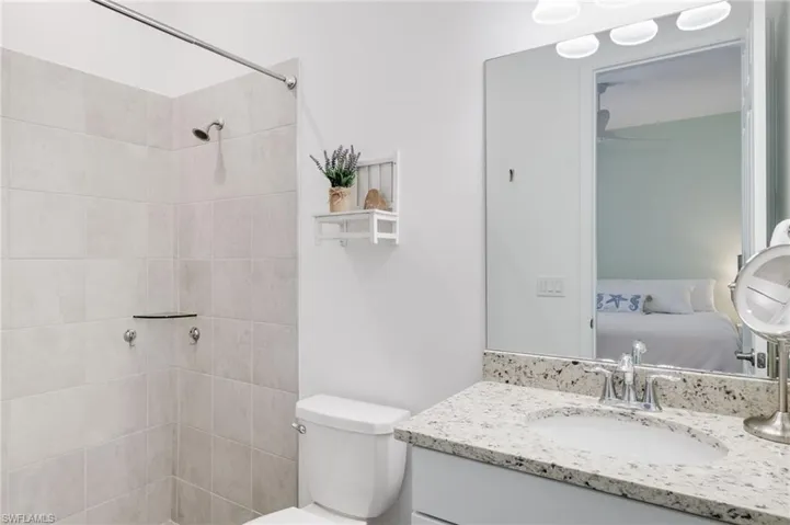 Bathroom with vanity, a tile shower, and toilet