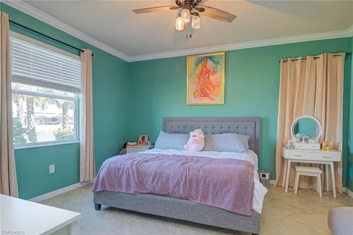 Spacious room featuring light tile flooring, crown molding, a window with blinds, and a built-in ceiling fan with integrated lighting