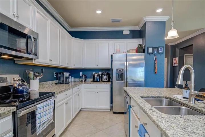 Kitchen featuring white cabinetry, granite countertops, stainless steel appliances, and recessed lighting