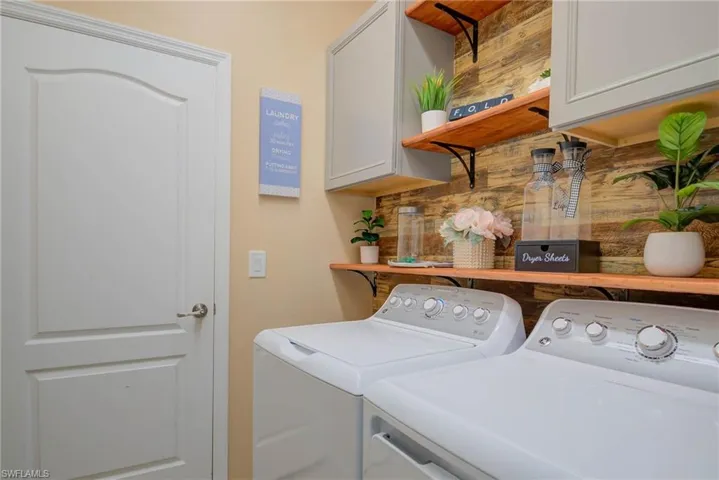 Laundry area featuring wood-finish accent wall, wood-finish open shelving, and light gray cabinetry