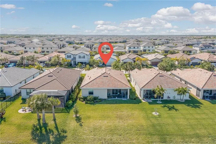 Rear exterior featuring a screened lanai, mature palm trees, and a spacious green lawn